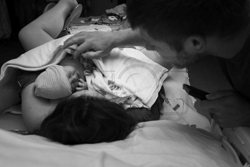 Medical staff attending to a patient in labor on a hospital bed.