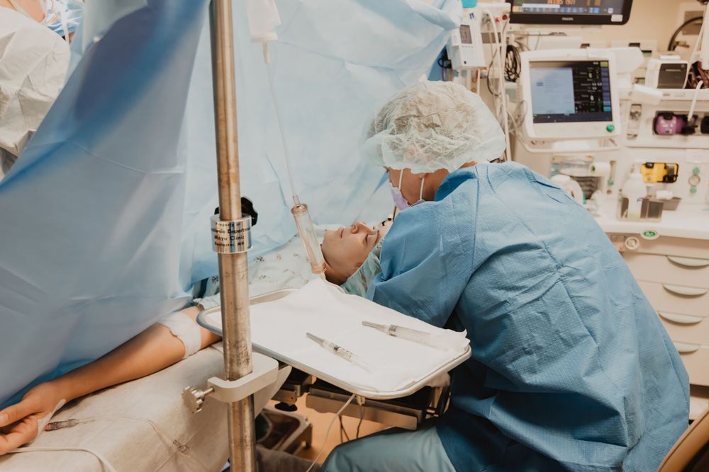 Medical professional in surgical scrubs performs a medical procedure in an operating room setting.