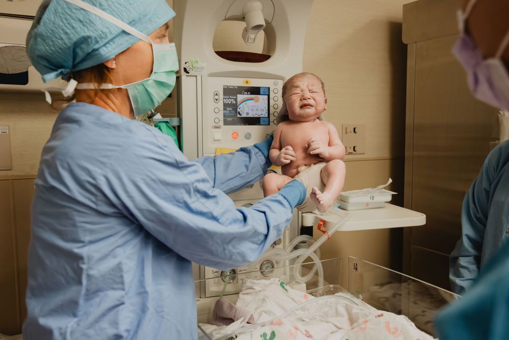 Medical staff examines a newborn baby in a hospital delivery room.