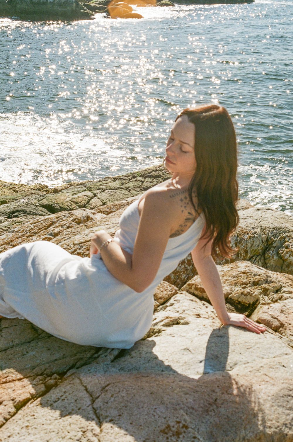 Sunlit rocks by sparkling ocean waters create a serene coastal scene.