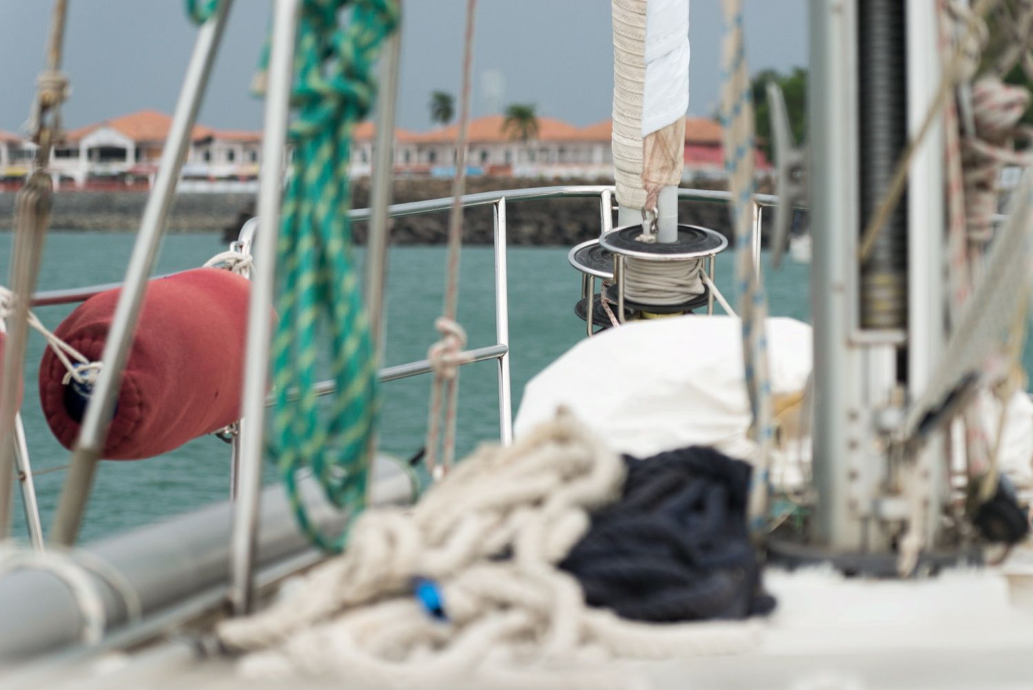 Nautical equipment and ropes on boat deck with waterfront in background.