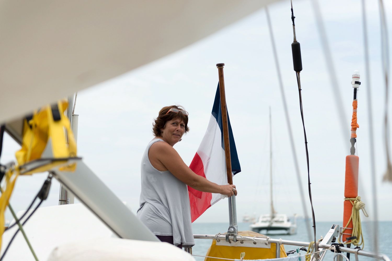 Person adjusting nautical flags on a sailboat mast.