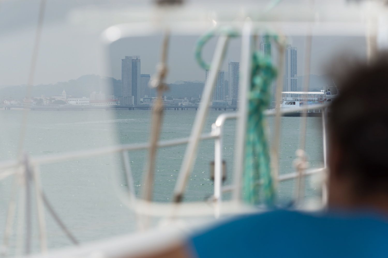 Blurred view of city skyline through boat rigging and ropes.