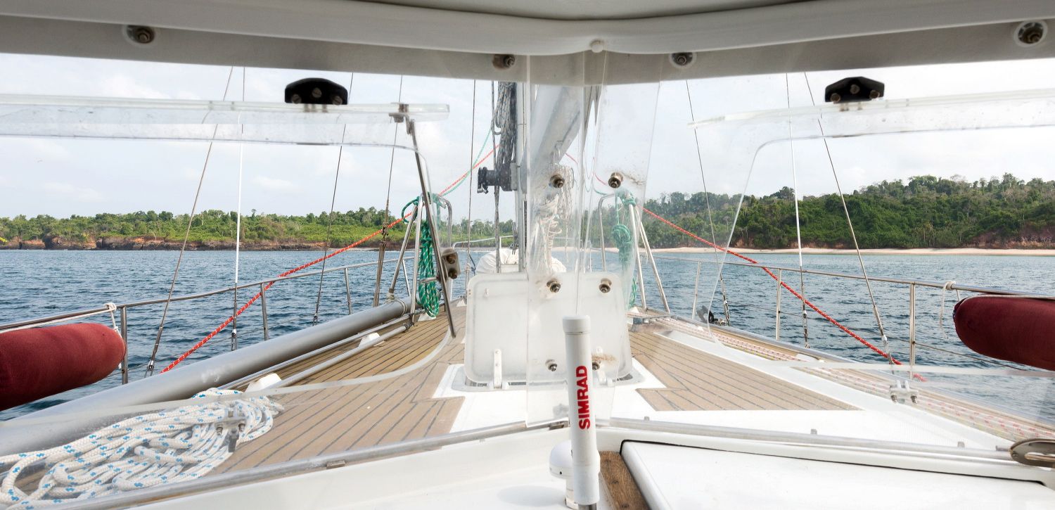 View of a sailboat's wooden deck with navigation equipment and safety gear.