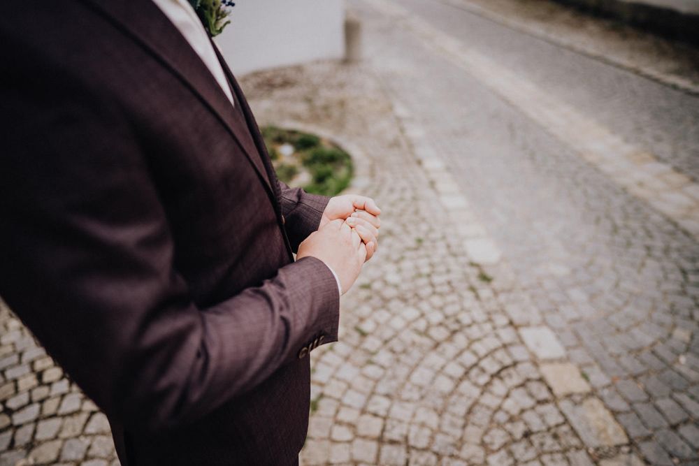 Close-up view of hands holding ring box on cobblestone street during wedding ceremony.