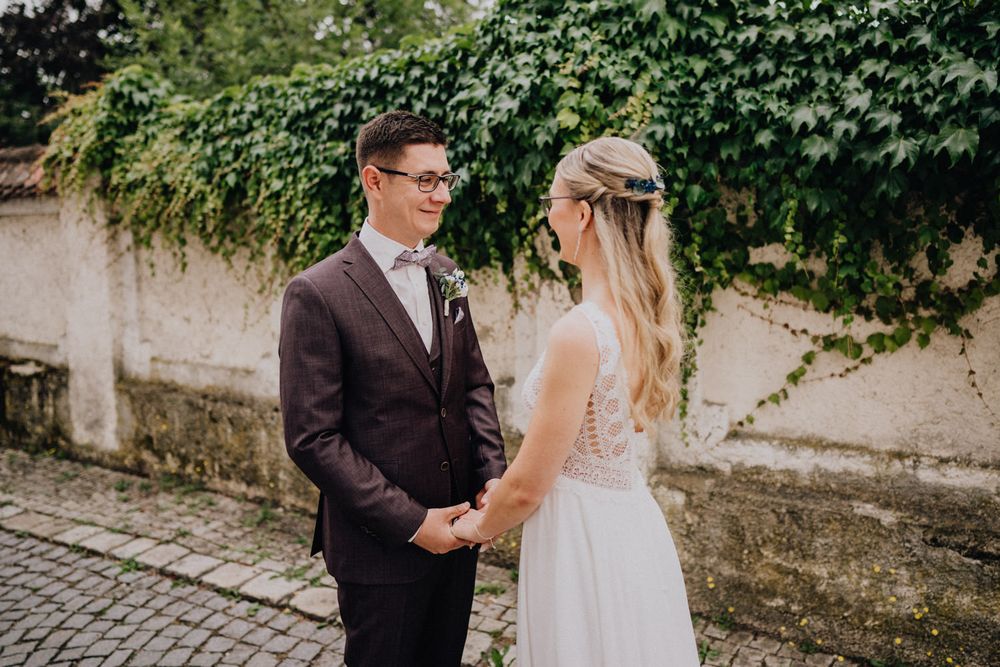 A romantic wedding moment captured against a backdrop of climbing vines and stone walls.
