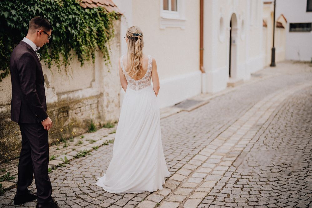 A romantic wedding scene on a cobblestone street with ivy-covered walls.