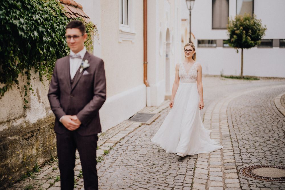 Wedding couple posing on European cobblestone street with vintage architecture.