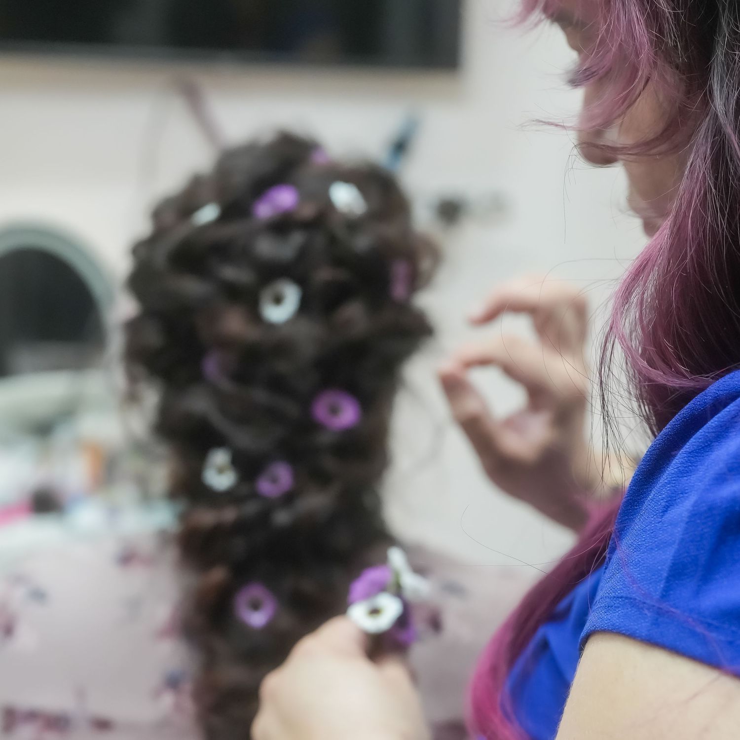 Purple flowers decoratively arranged in dark braided hair.
