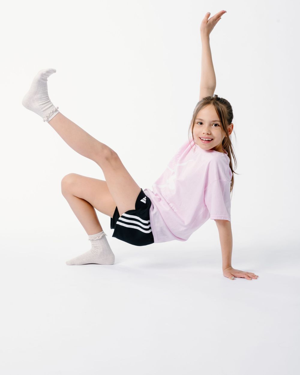 Dancer in white and black outfit demonstrates floor movements in contemporary dance sequence.