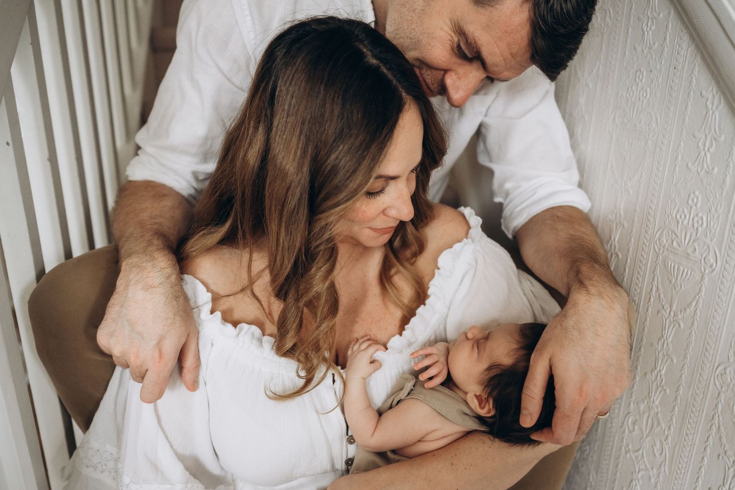 A couple looking lovingly at their new born girl  during their new born in home session in Kent