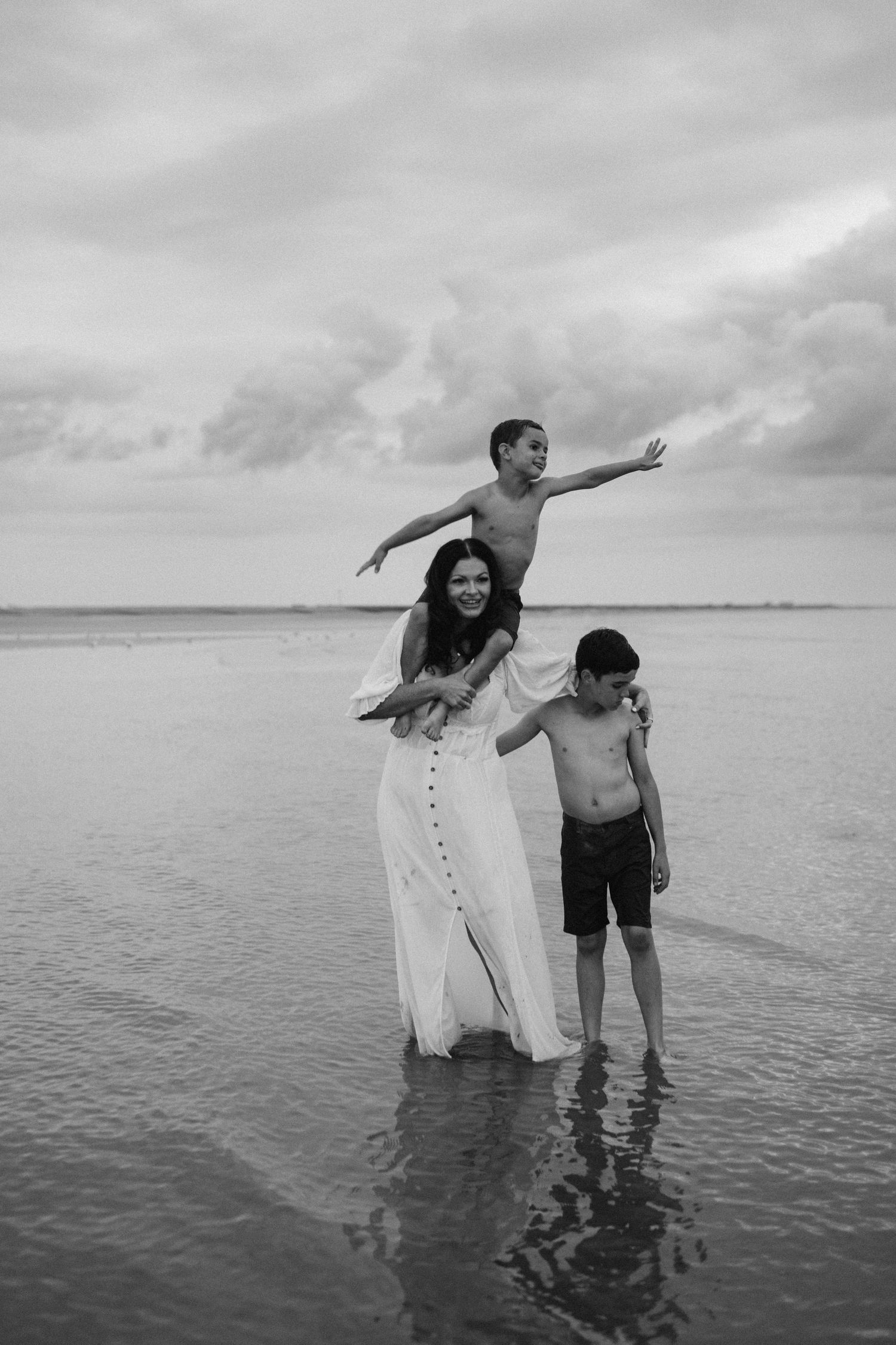 a mother carrying her youngest son on her shoulders and holding her other son by his shoulders during their family photo session in Kent