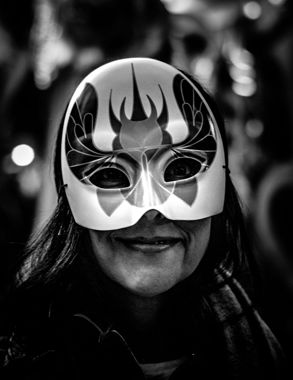 Black and white photograph of someone wearing an ornate deer-themed masquerade mask.