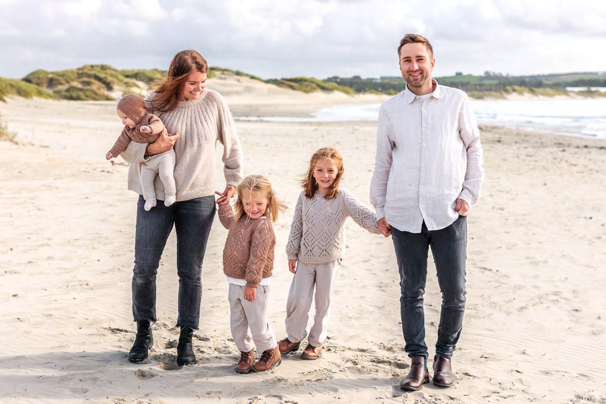 Familie på fem går hånd i hånd på Solastranden.