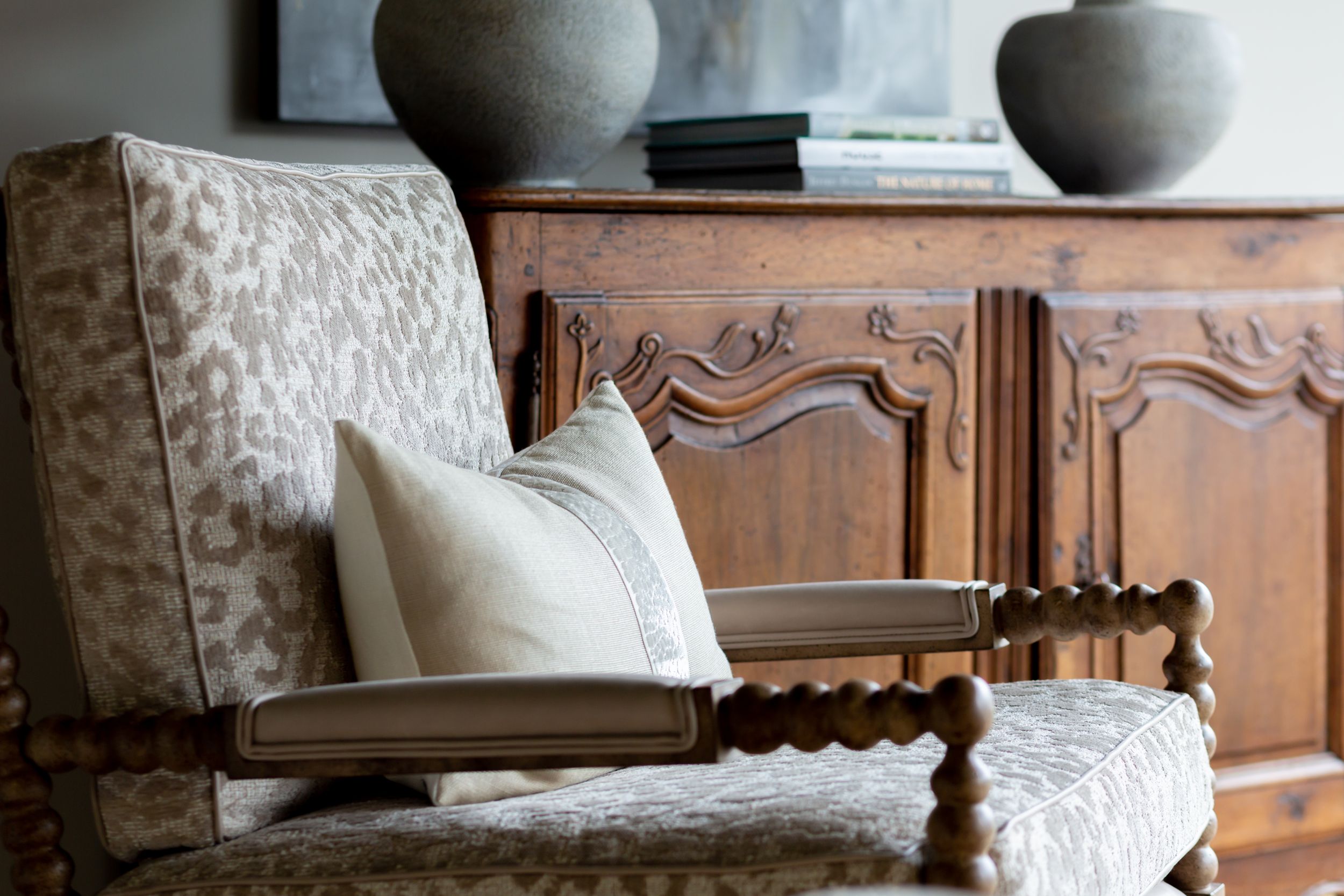 Elegant upholstered chair with textured cushions sits in front of wooden cabinet with decorative vases.
Commercial Photography