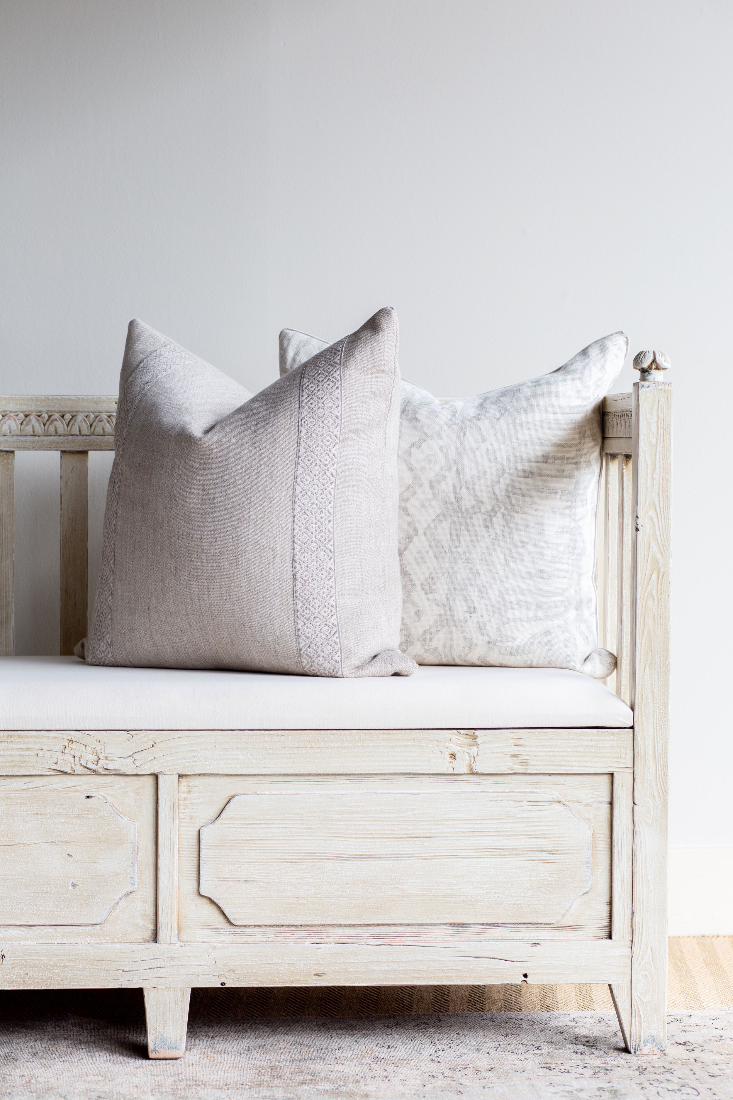 White distressed bench with neutral linen pillows against minimal white wall.
Commercial Photography