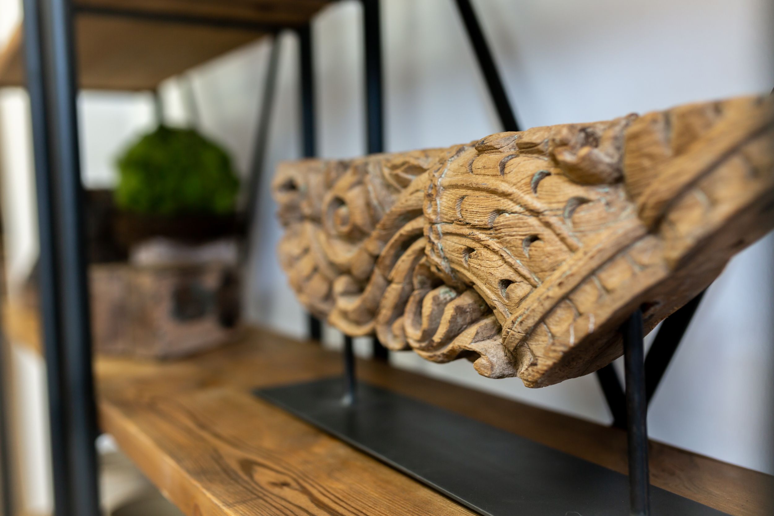 Decorative carved wooden architectural detail mounted on a black stand displayed on a shelf.
Commercial Photography