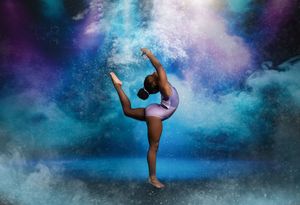 A silhouetted dancer performs graceful poses against a mystical blue and purple cloudy backdrop.