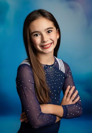 A series of portrait photos featuring someone in a navy blue polka dot dress with sheer sleeves against a blue background.