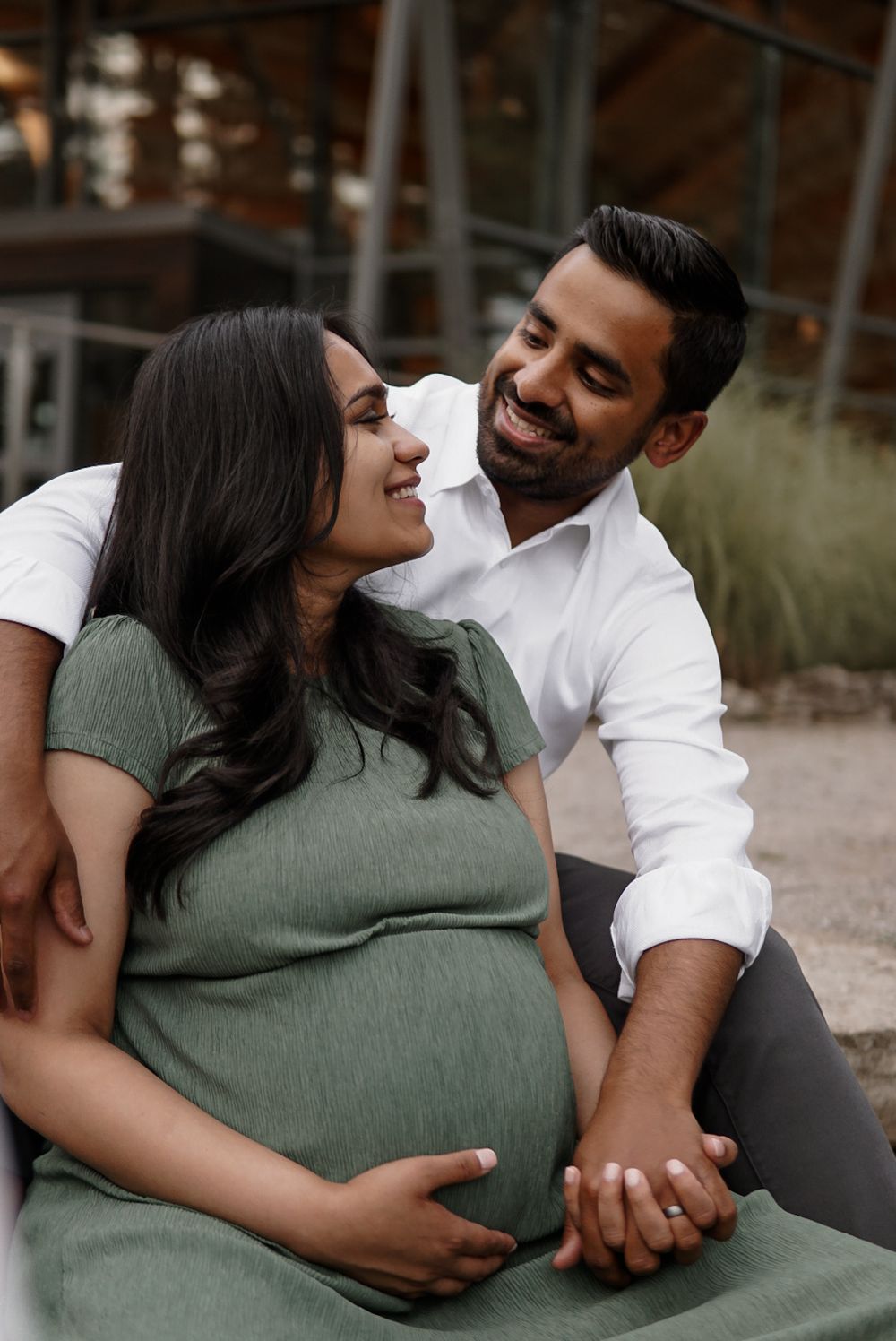 An expecting couple seated together, smiling