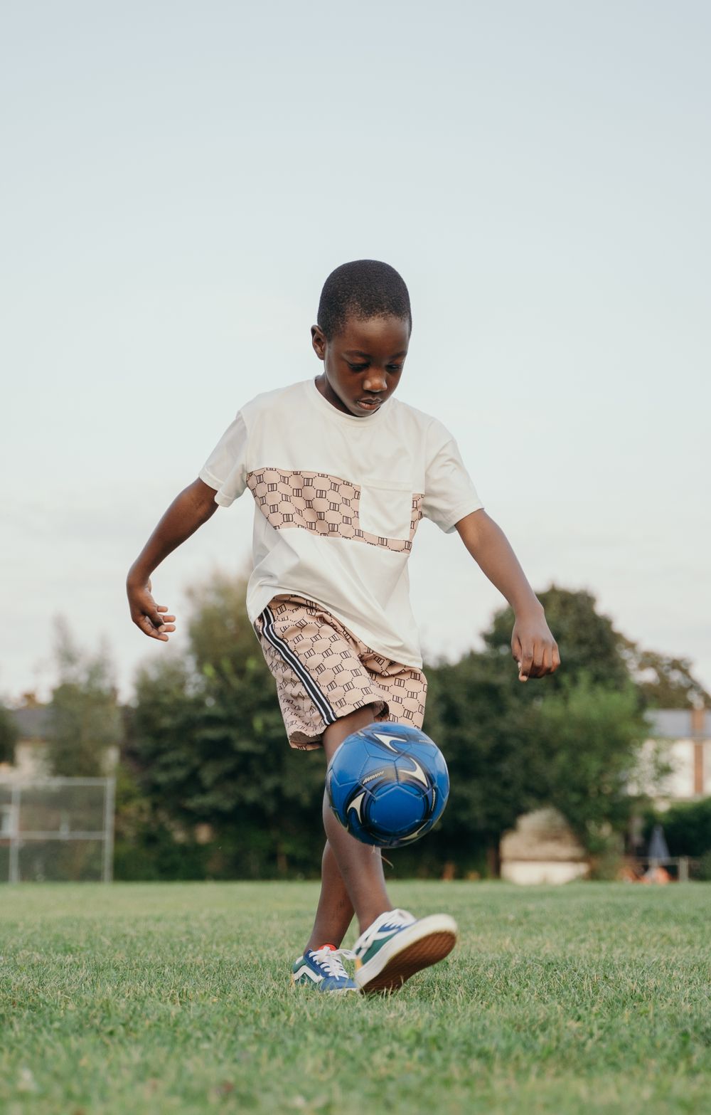 A young boy juggling a soccer ball in the park
