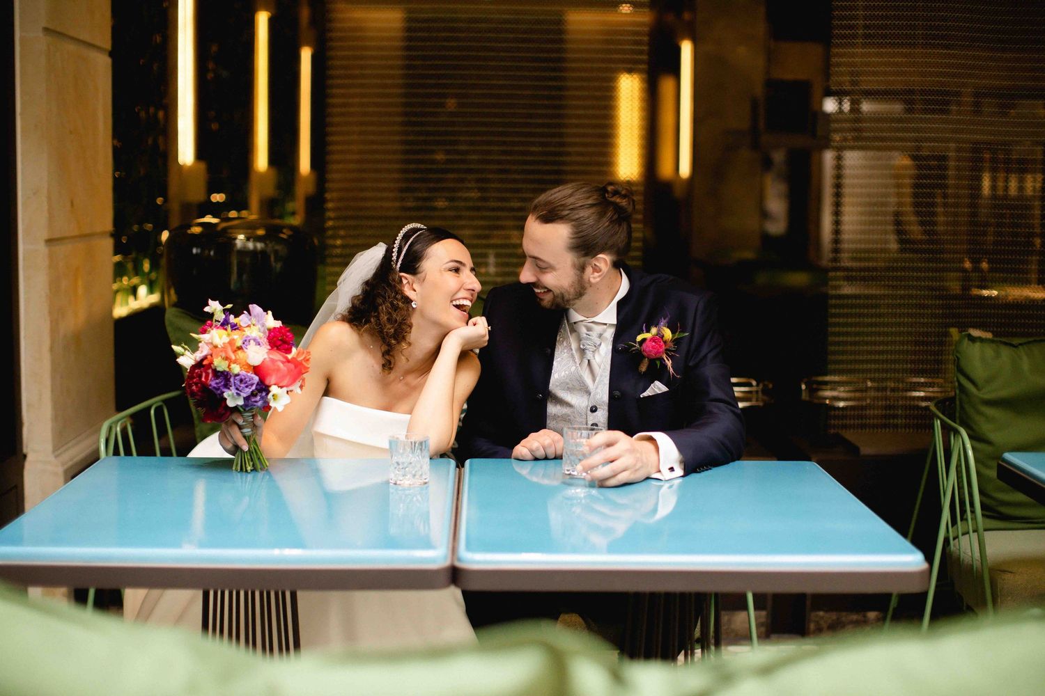 A couple shares an intimate moment at a lounge area with glowing lights in the background.