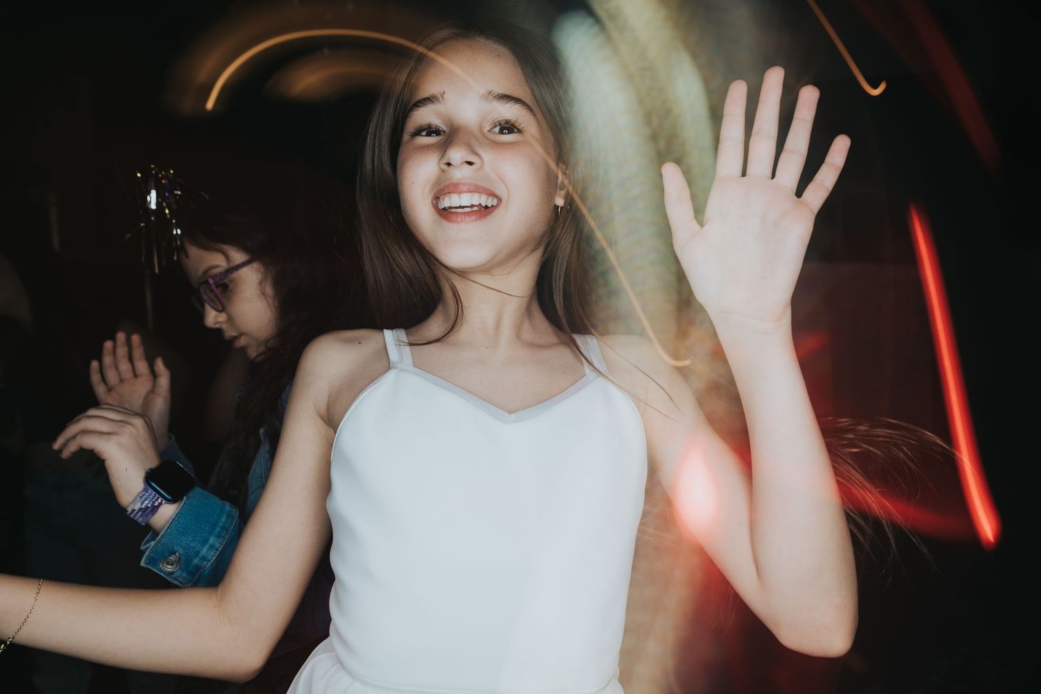 Joyful dancing captured in white attire with motion blur and party lights.