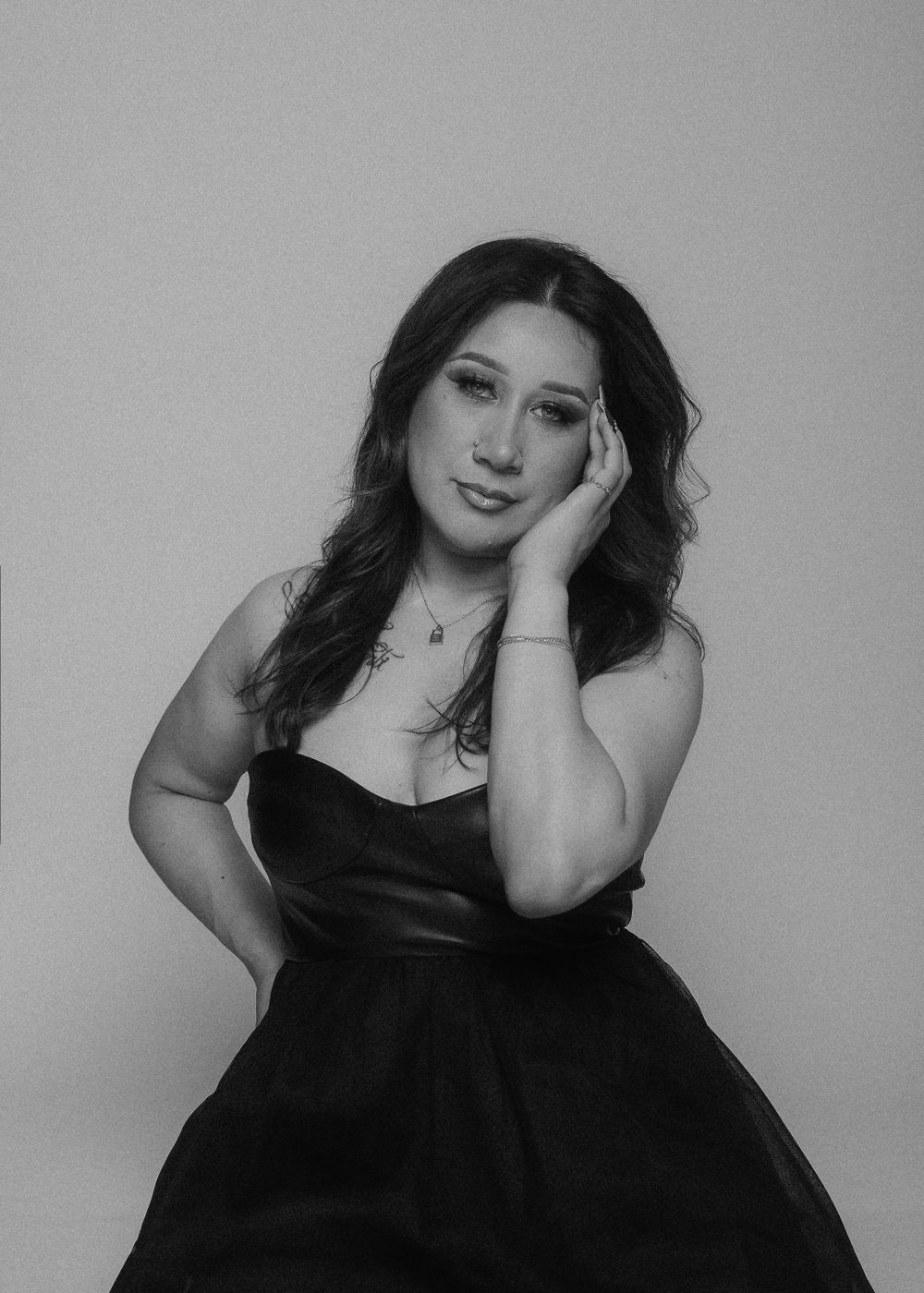 Studio portrait of person in black strapless dress with soft dreamy expression.