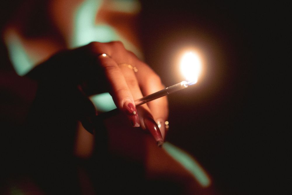 Close detail shot of hands holding a lit match with blurred fire effects.