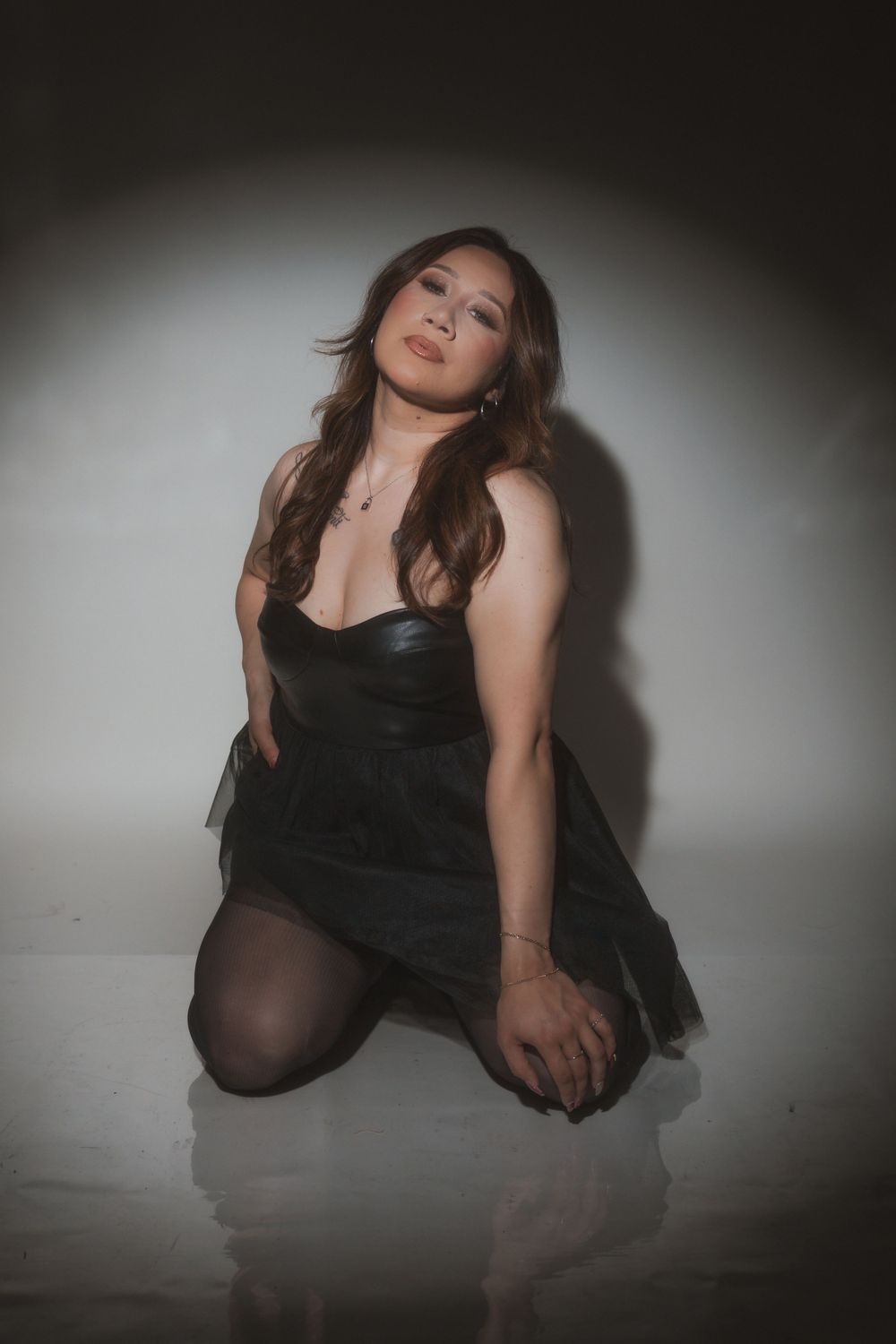 Moody fashion portrait with dramatic lighting showcasing a black dress and evening makeup.