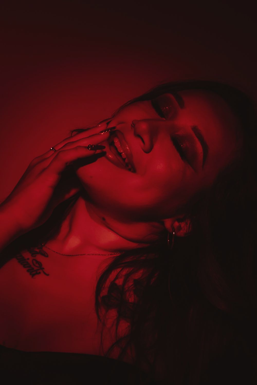 Dramatic closeup portrait bathed in red light with expressive pose.