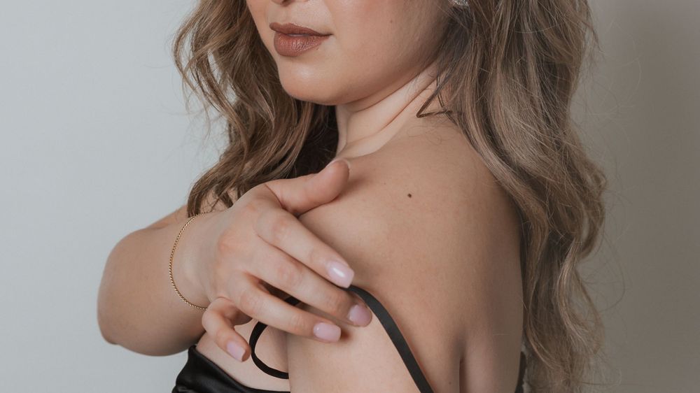 Close up portrait showing bare shoulders and wavy hair with woman wearing black evening dress.