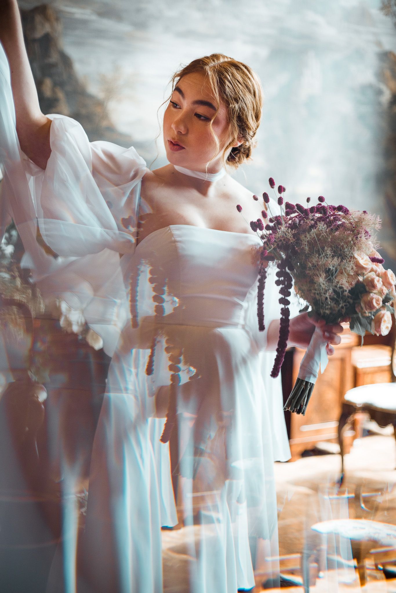 A dreamy, ethereal bridal portrait, woman in white dress holding bouquets in soft lighting.