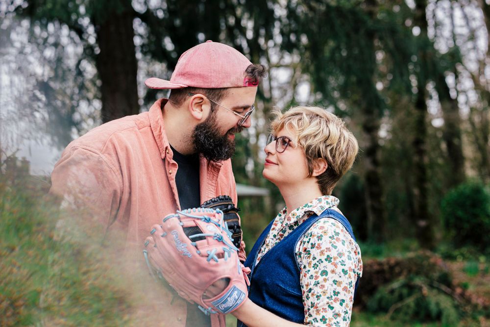 A tender moment of affection shared between two people standing in a serene forest setting.