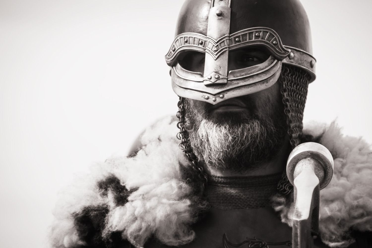 Black and white portrait of a bearded man wearing a Viking helmet and chainmail armor.