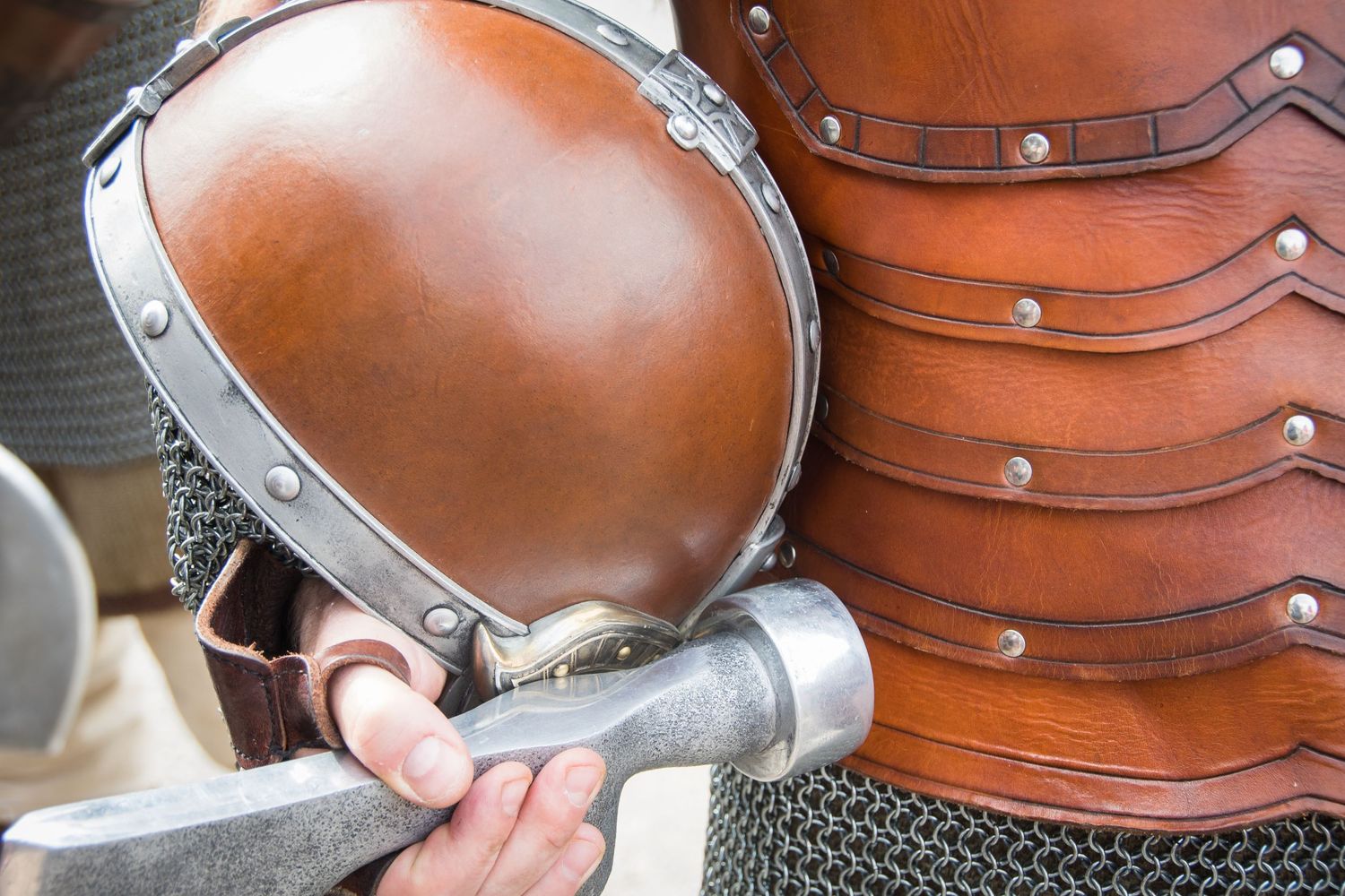 Close-up of medieval knight holding a sword wearing leather armor and chainmail.