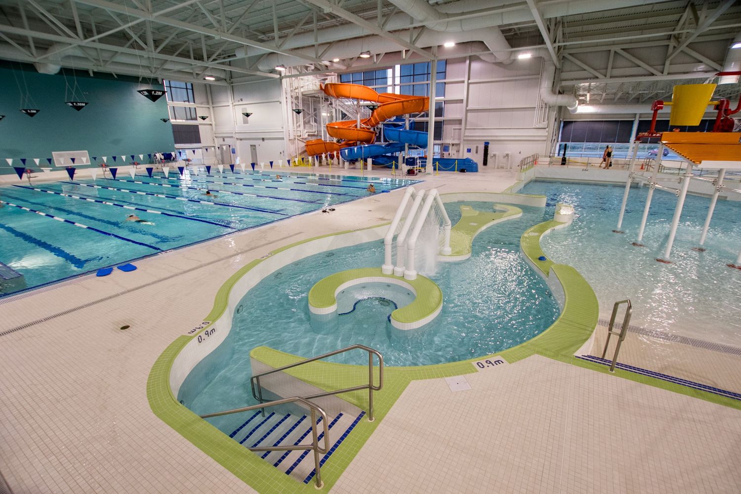 Indoor recreation center pool with lazy river, lap lanes, and orange water slide.