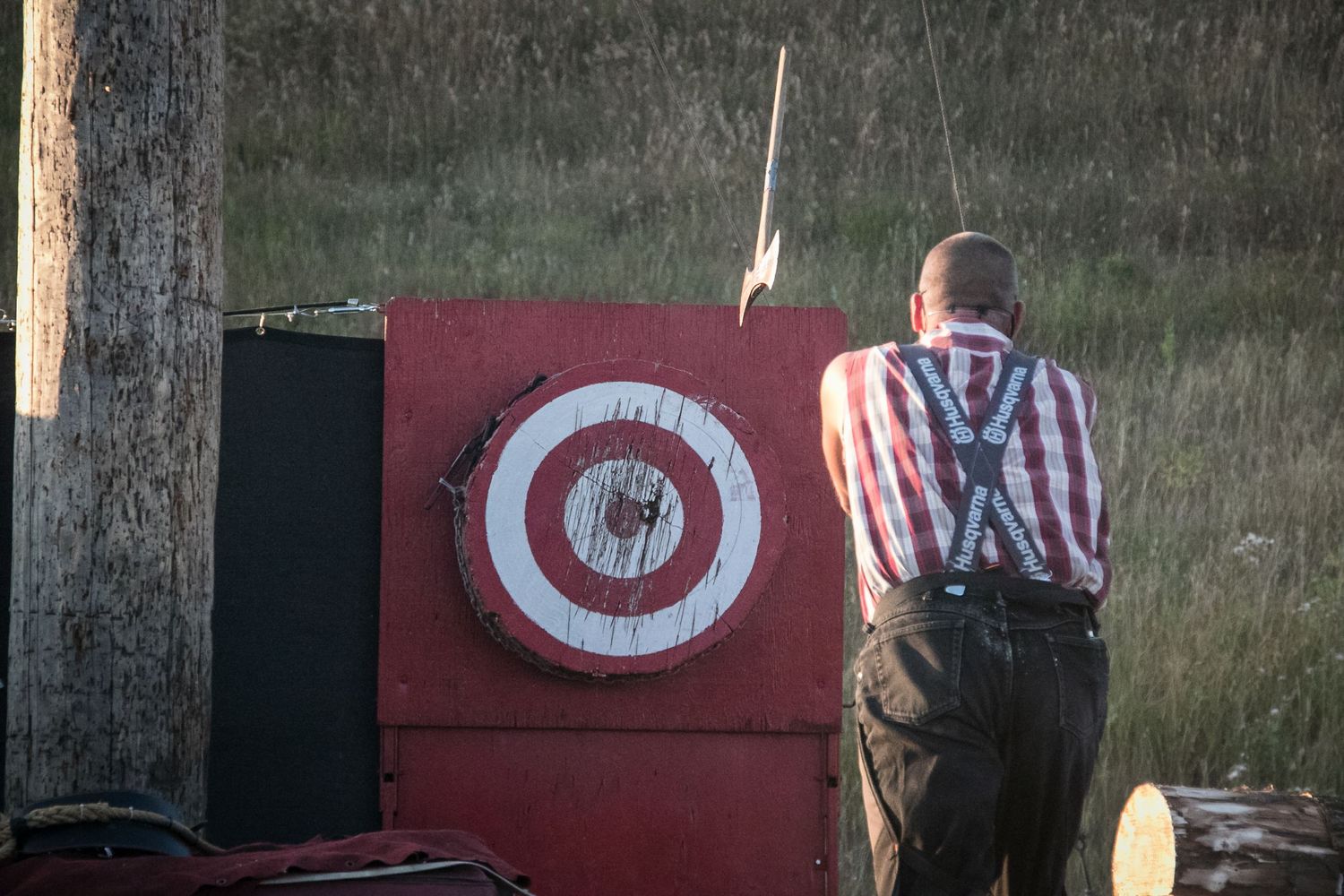 Axe thrower competing at target board during outdoor lumberjack competition event.