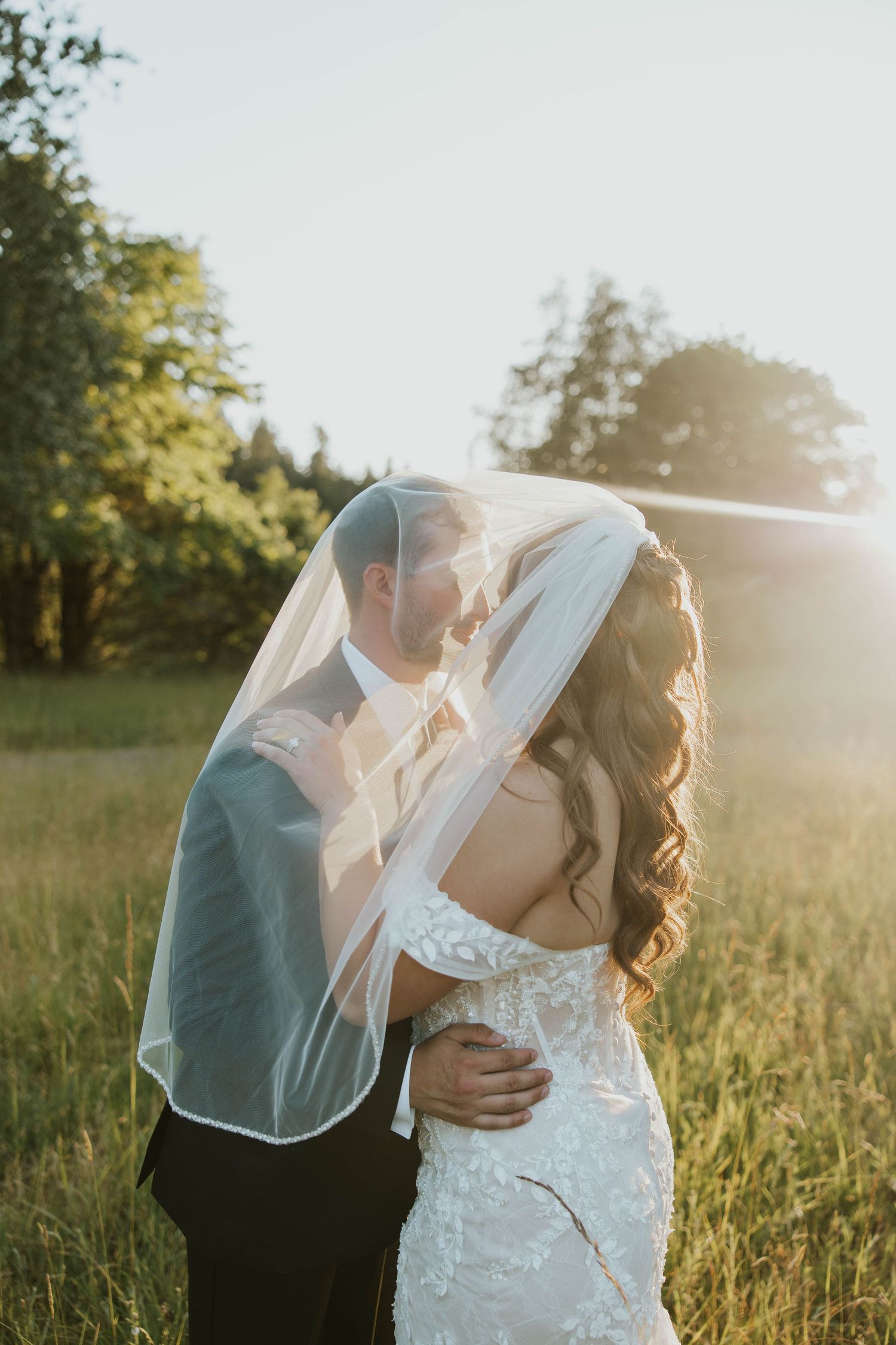 Wedding couple shares romantic moments in a sun-drenched meadow at golden hour.
