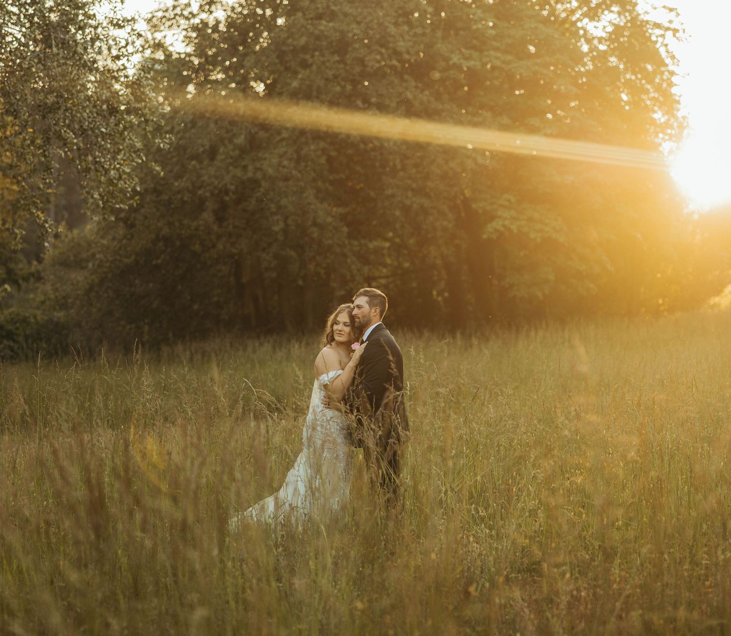 Wedding couple embracing in a golden meadow during sunset.