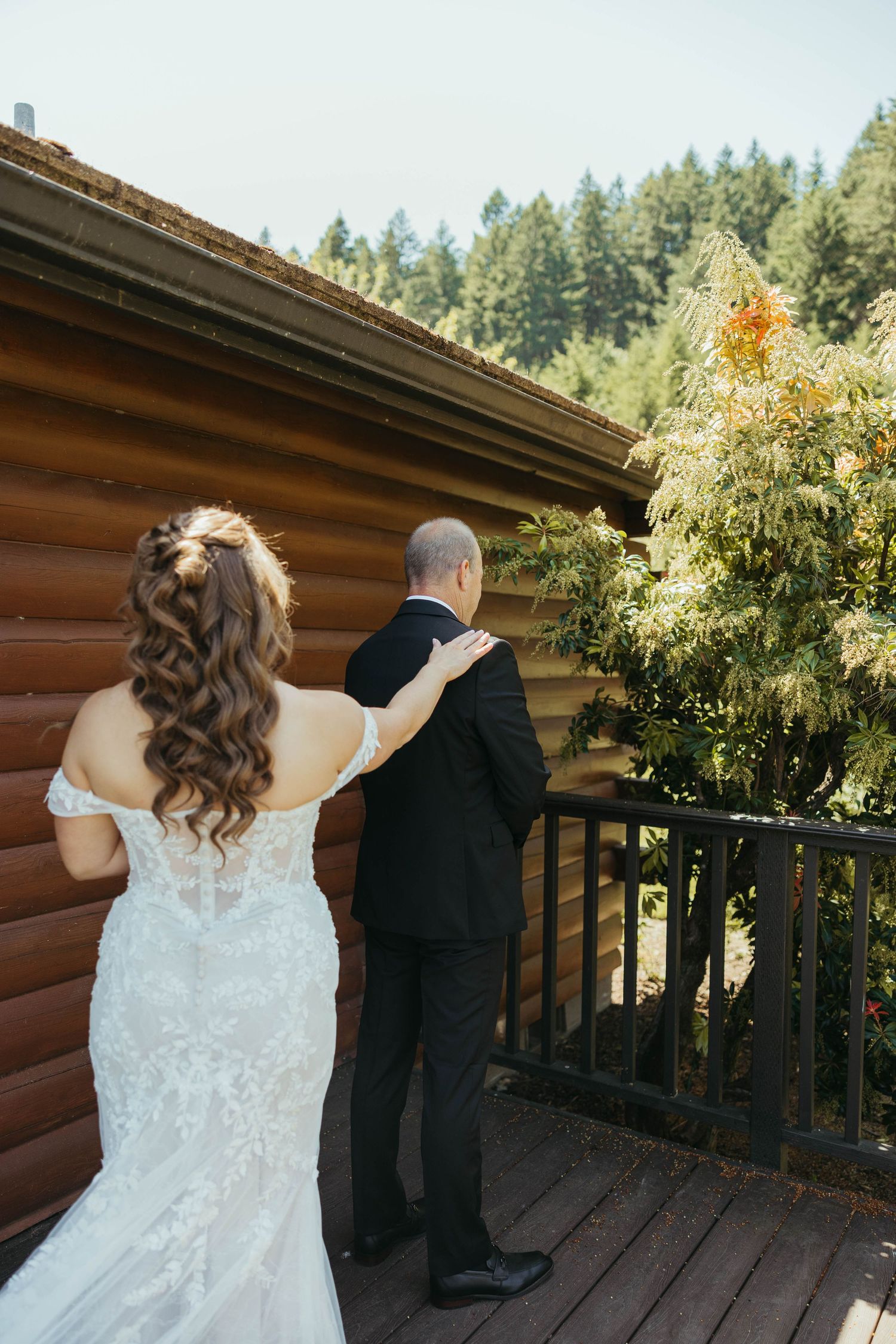 First look moment captured on rustic cabin deck surrounded by pine trees.