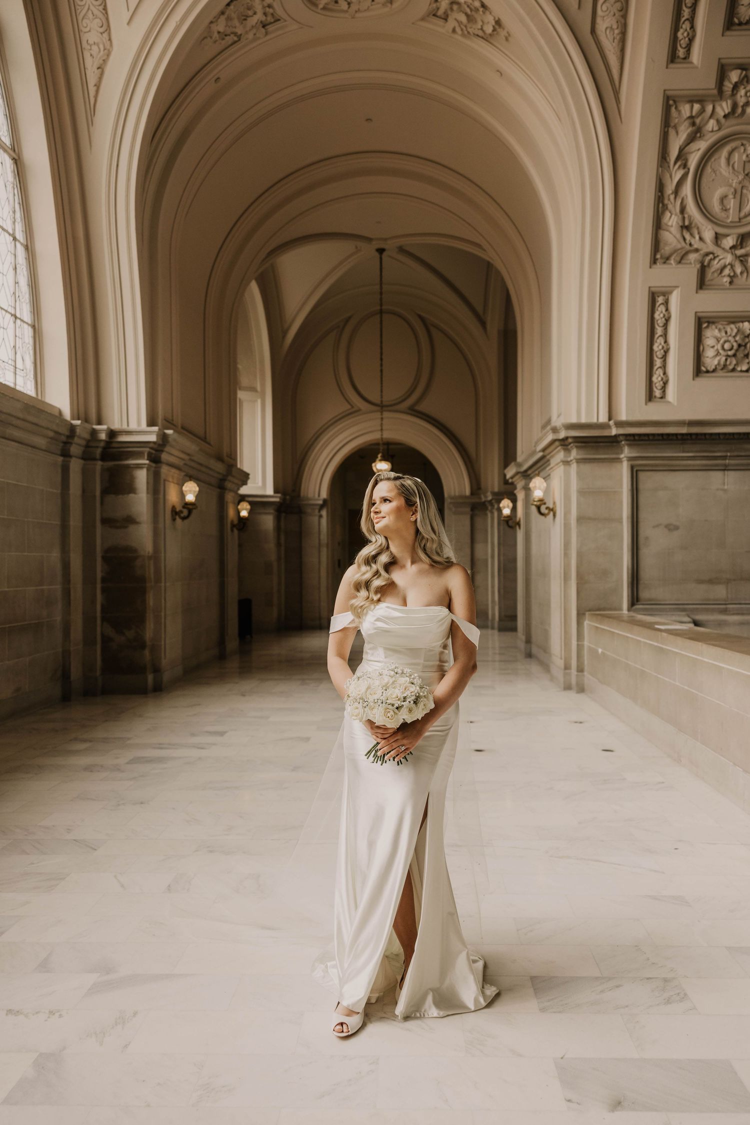 Elegant bridal portraits in ornate classical architecture hallway with arches.