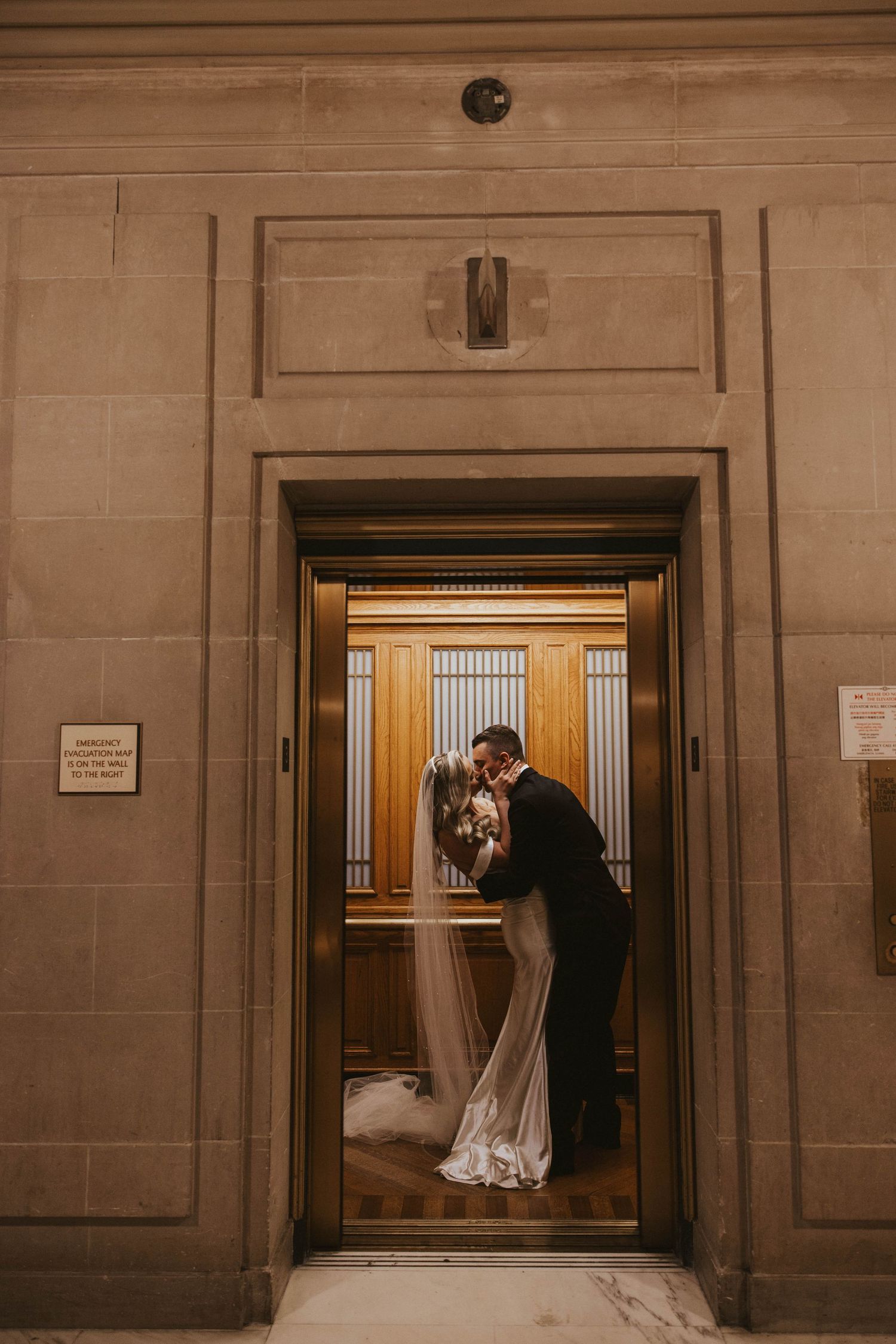 Wedding couple sharing intimate moment through vintage elevator window frame.