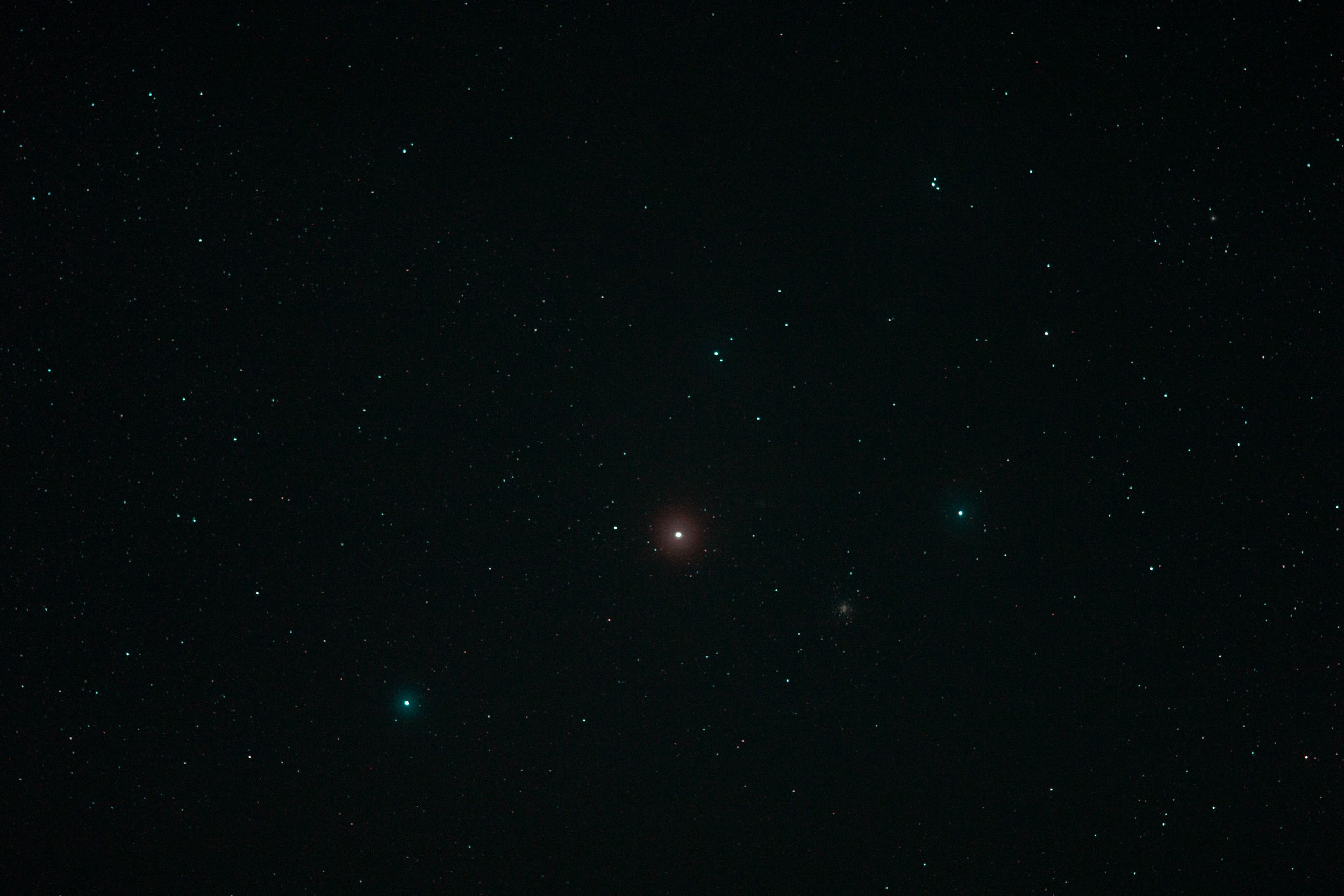 Bright red star glows in deep space surrounded by distant blue stars.