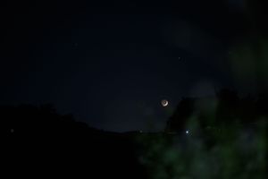 Crescent moon and bright star or planet visible in the dark night sky.