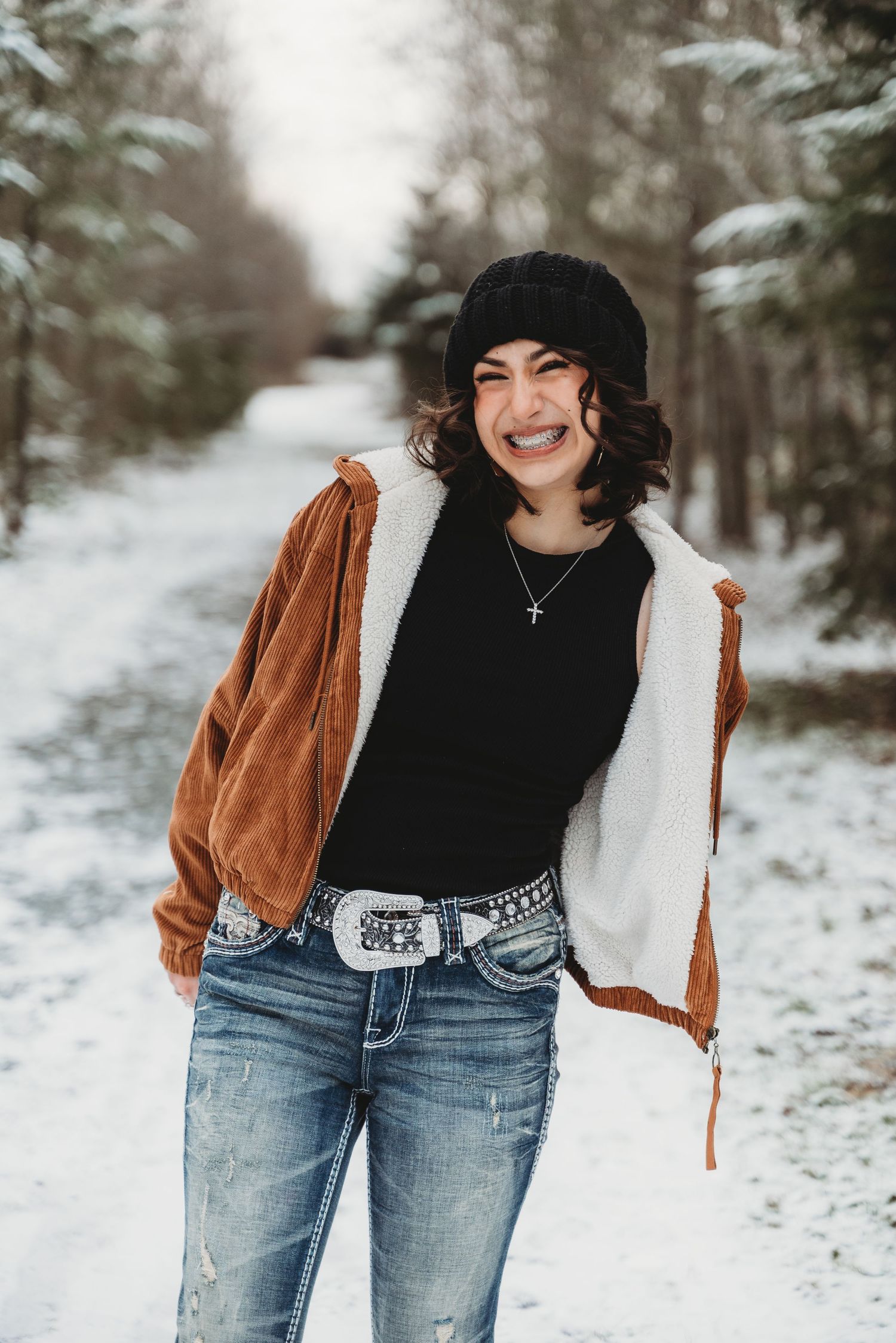 senior girl smiles backed by a snowy tree lined path at Northern State Rec Area