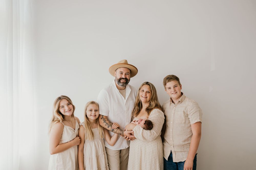 A family shares joyful moments together in a bright room with white walls during a casual photo session.