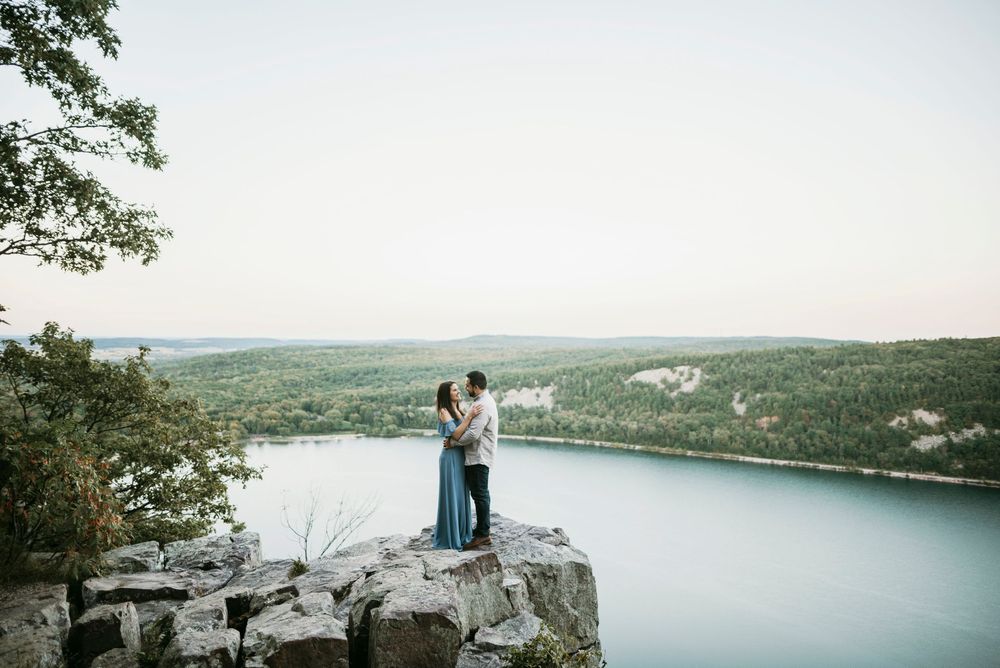 Scenic mountaintop engagement photoshoot overlooking a serene lake in a romantic outdoor setting.