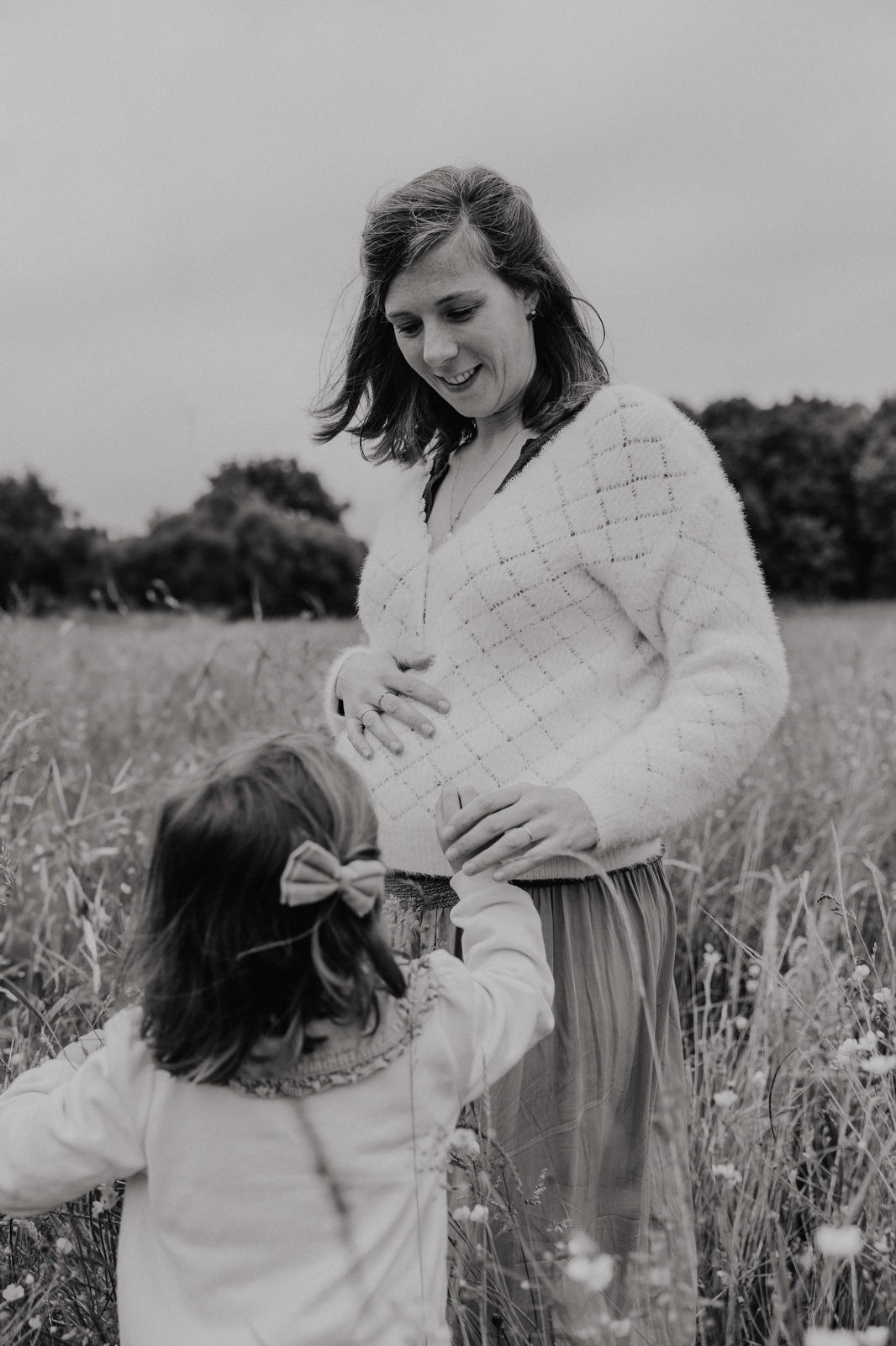 Black and white photo series showing joyful moments between parent and child playing together in a wildflower meadow.