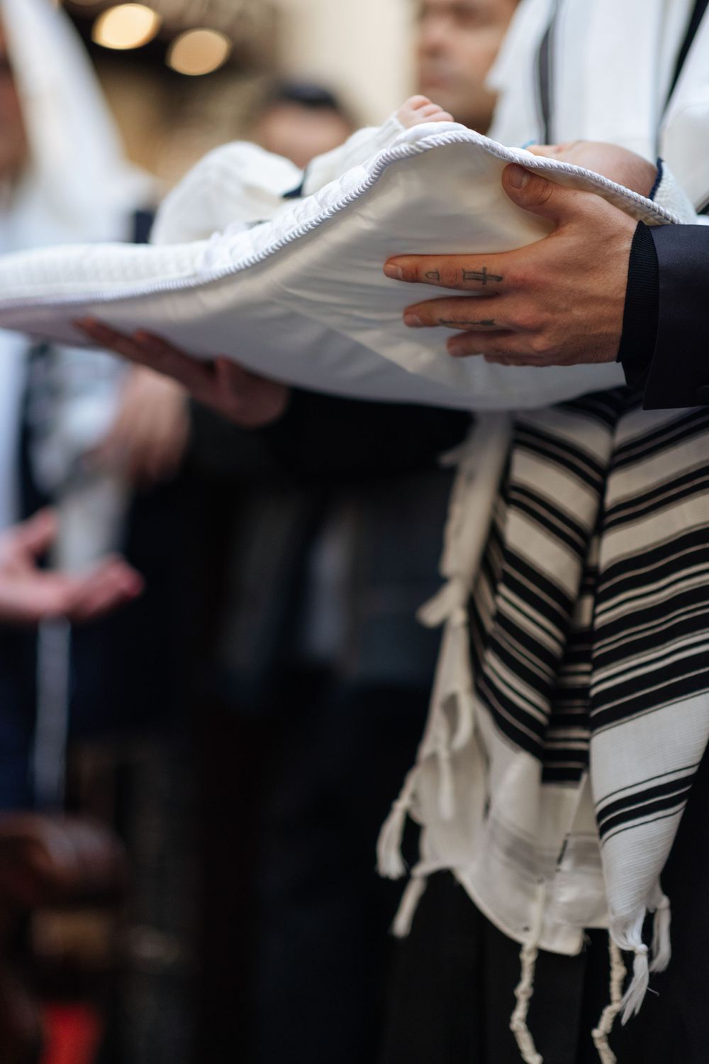 Close-up of hands holding a prayer book while wearing a traditional Jewish tallit prayer shawl during religious service.